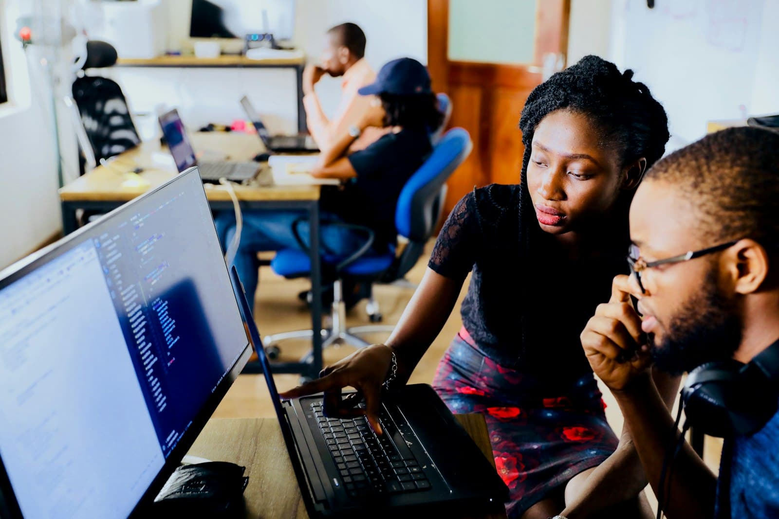 Two students collaborating closely over a laptop in a shared study space